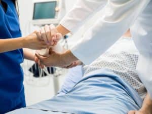 person in hospital bed getting arm wrapped after burn injury