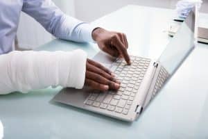 person typing with cast from workplace injury